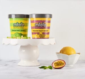 two pints of miele on a cake stand next to a bowl of passion fruit sorbet