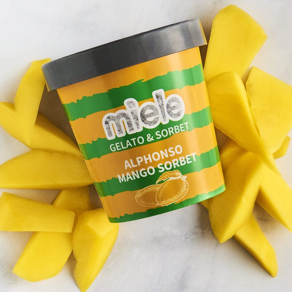 miele mango sorbet pint on top of sliced mangos